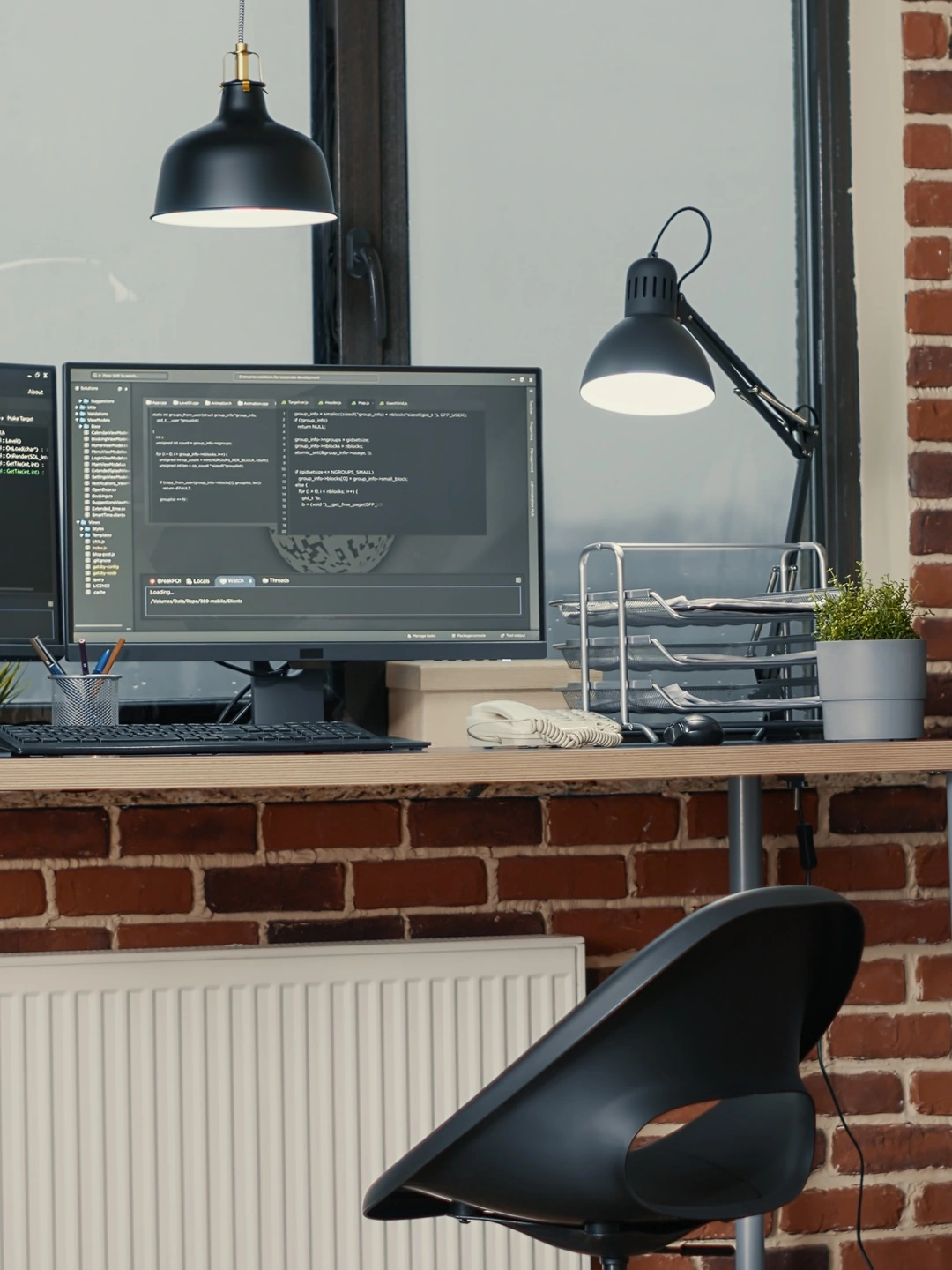 A developer workstation with several monitors showing code, in a quiet office in the evening