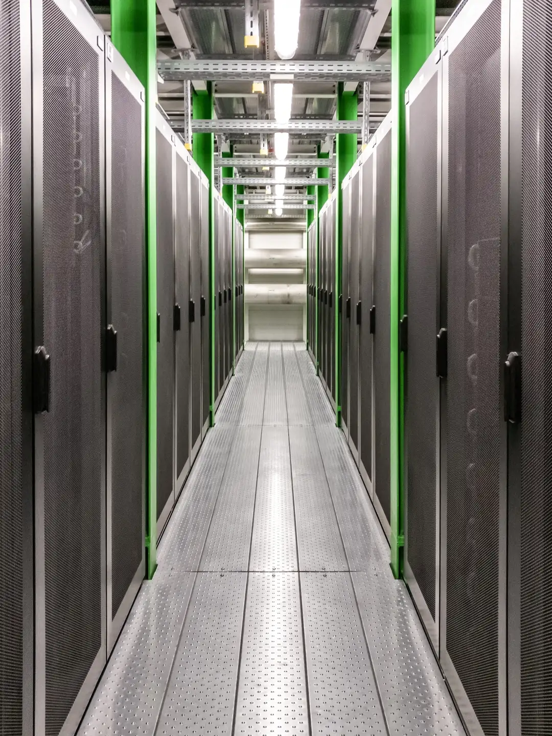 A corridor between server racks in a data centre under ordinary working light